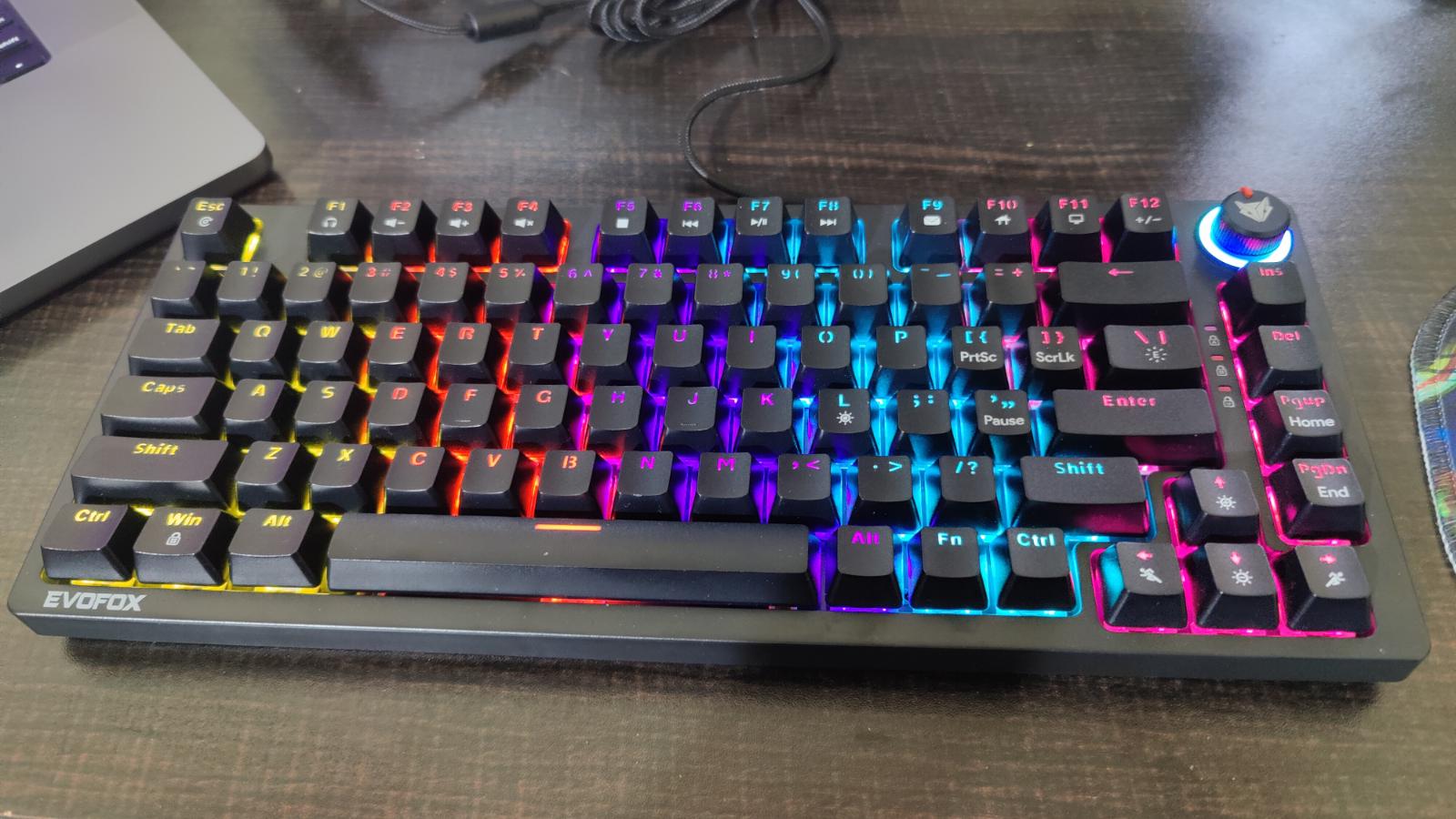 A wired black-coloured mechanical keyboard with its rainbow backlights on